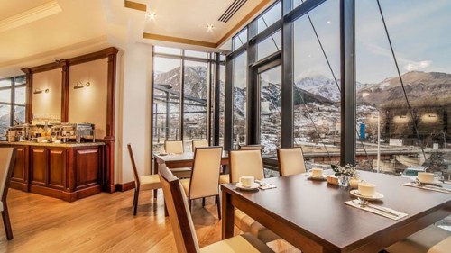 The dining room of the Porta Caucasia hotel offers panoramic views of the Kazbegi Mountains, a popular skiing and hiking destination.